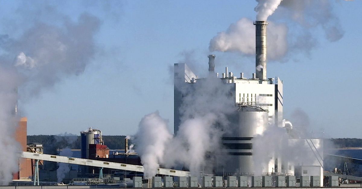 Pappersbruk med flera skorstenar som släpper ut tät vit ånga och utsläpp
